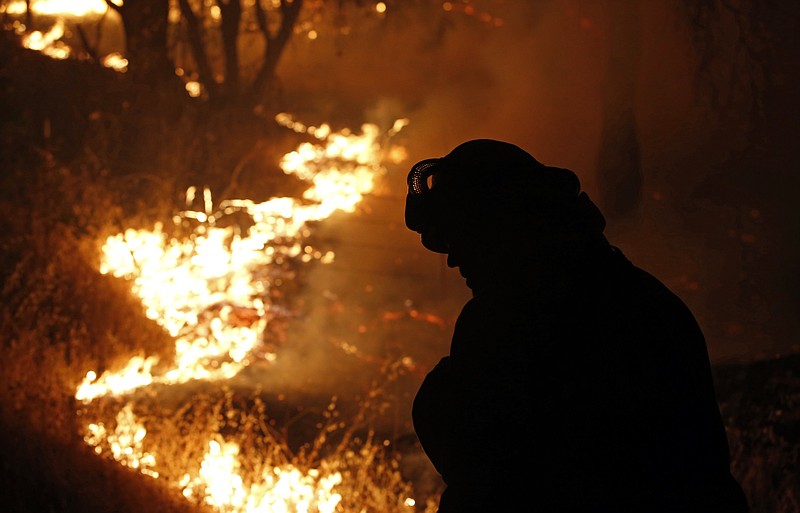 
              FILE - In this Sept. 11, 2015, file photo, a firefighter turns his head from flames of the Butte Fire burning near San Andreas, Calif. The California Department of Forestry and Fire Protection released a report Thursday, April 28, 2016, detailing the cause of the fire in Calaveras and Amador counties. (AP Photo/Rich Pedroncelli, File)
            