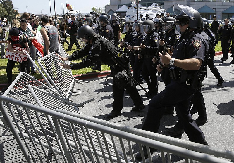 
              Police officers push down barricades used by a group protesting Republican presidential candidate Donald Trump outside of the Hyatt Regency hotel during the California Republican Party 2016 convention in Burlingame, Calif., Friday, April 29, 2016. (AP Photo/Eric Risberg)
            