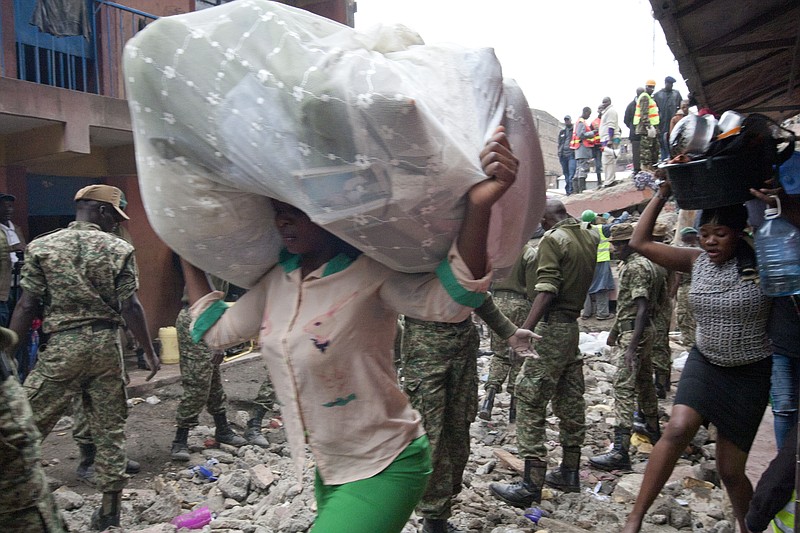 
              Survivors carry their belongings at the site of a building collapse in Nairobi, Kenya, Saturday, April 30, 2016. A six-story residential building in a low income area of the Kenyan capital collapsed Friday under heavy rain and flooding, trapping a number of people in the rubble, Kenyan officials said.(AP Photo/Sayyid Abdul Azim)
            