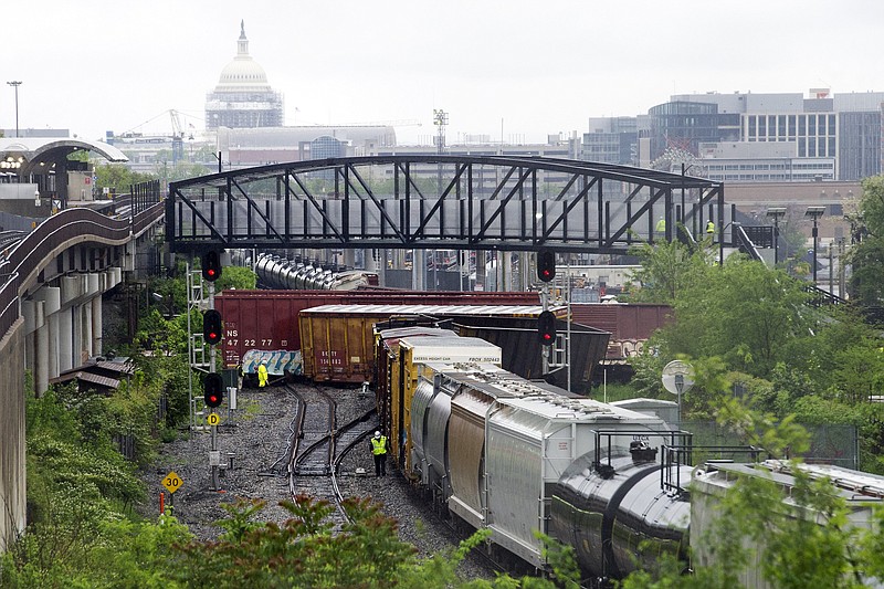Emergency personnel work at the scene after a CSX freight train derailed, spilling hazardous material, in Washington on Sunday, May 1, 2016. The Capitol is seen in the background. (AP Photo/Cliff Owen)