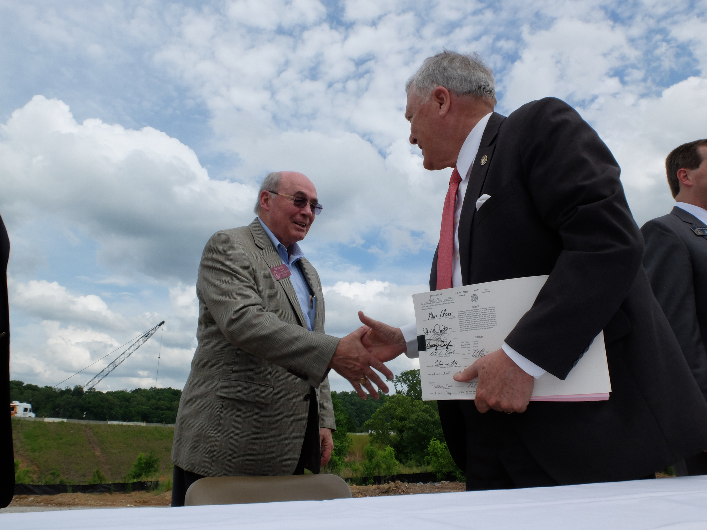 Georgia Gov. Nathan Deal shakes the hand of Rep. Tom Dickson, left, after signing the State Budget on an Interstate 75 entrance ramp Monday in Dalton Georgia.