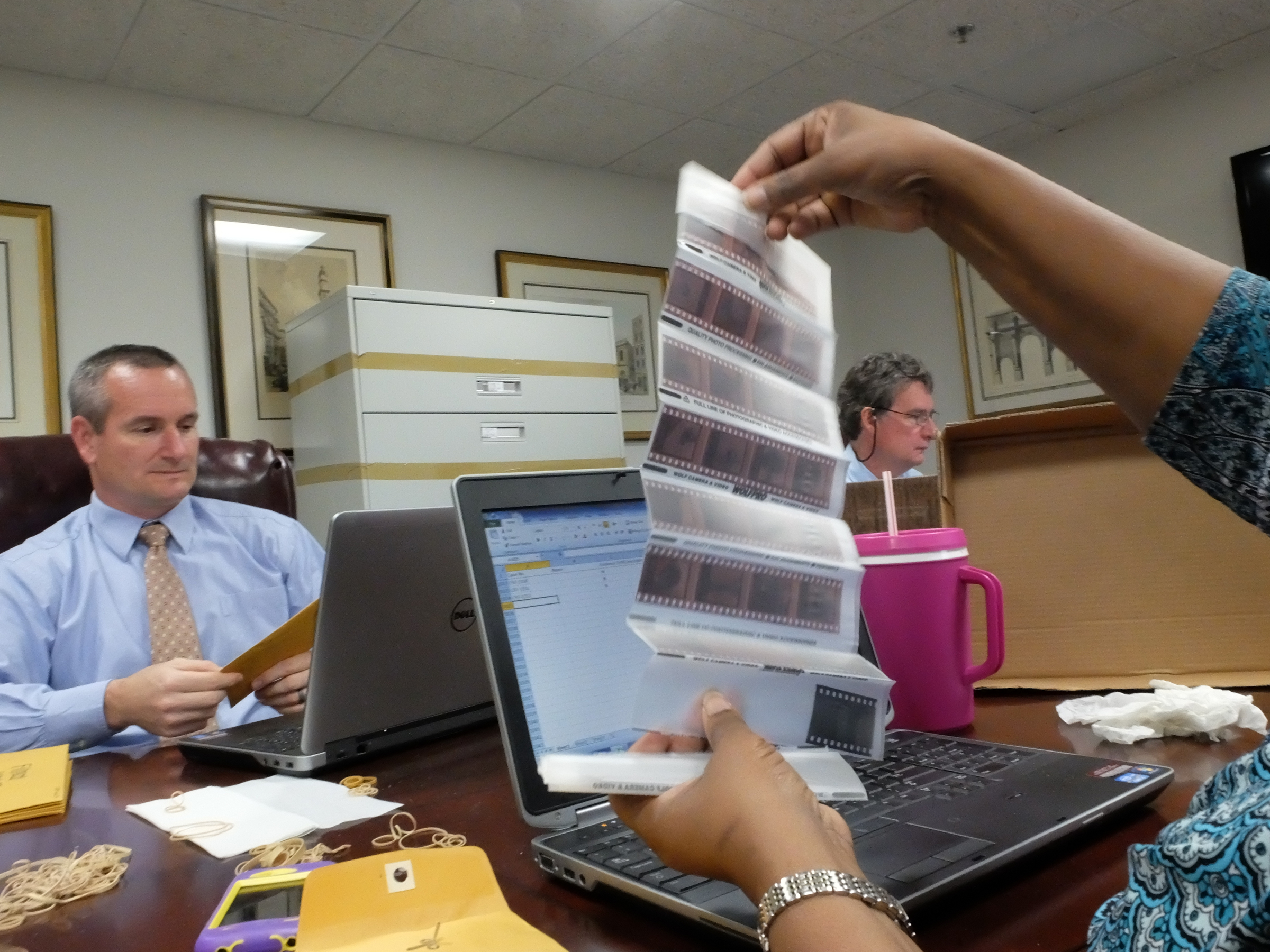 Johnetta Truss holds 35mm negatives that were evidence as Hamilton County auditors Chris McCollough, left, and Roger Kincer work at a table looking at thousands of evidence files recently removed from the Medical Examiners office.