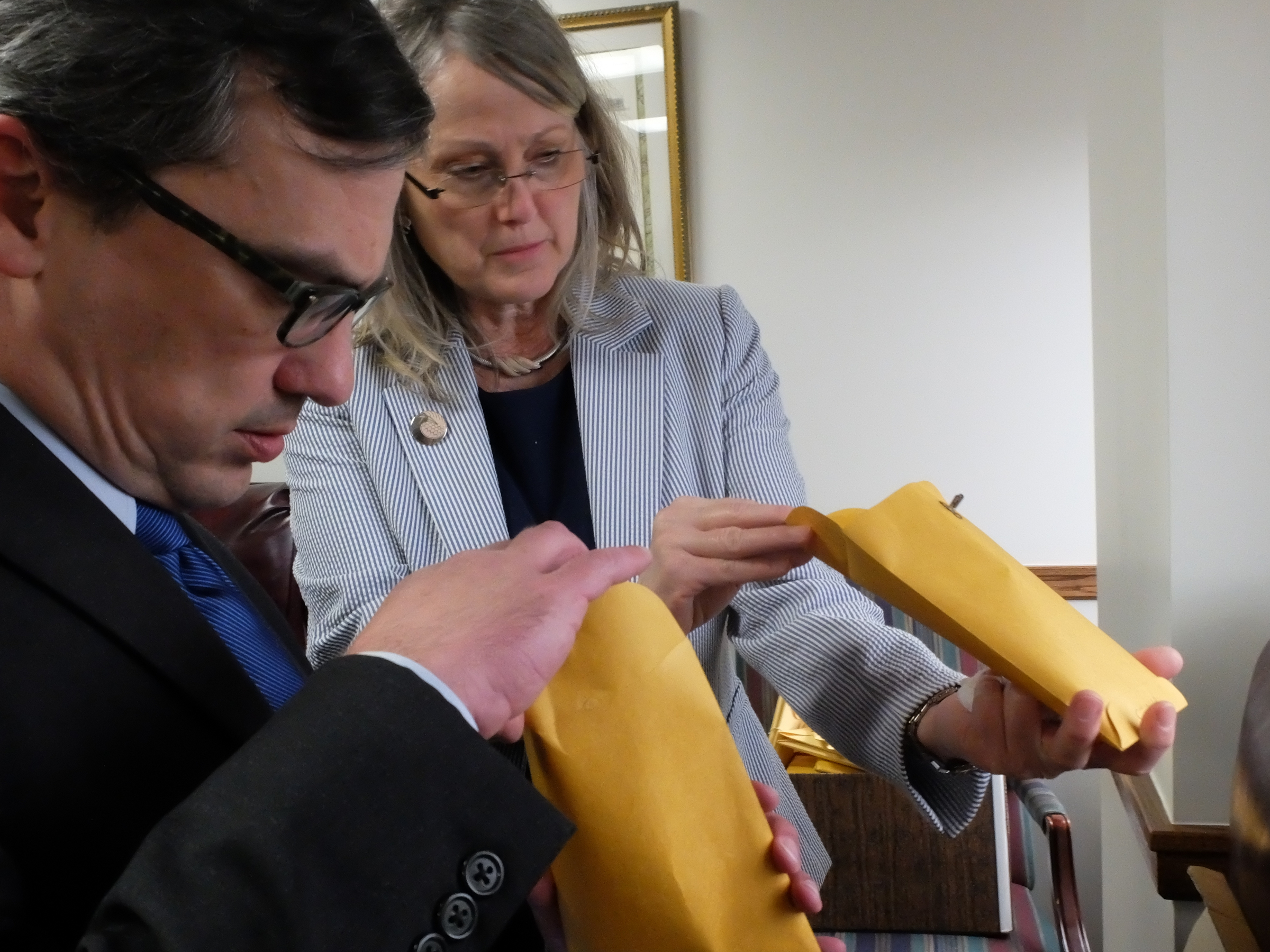 Attorney General Neal Pinkston, left, and Audit Manager Jenneth Randall peer into cold case envelopes recently removed from the Medical Examiners office.