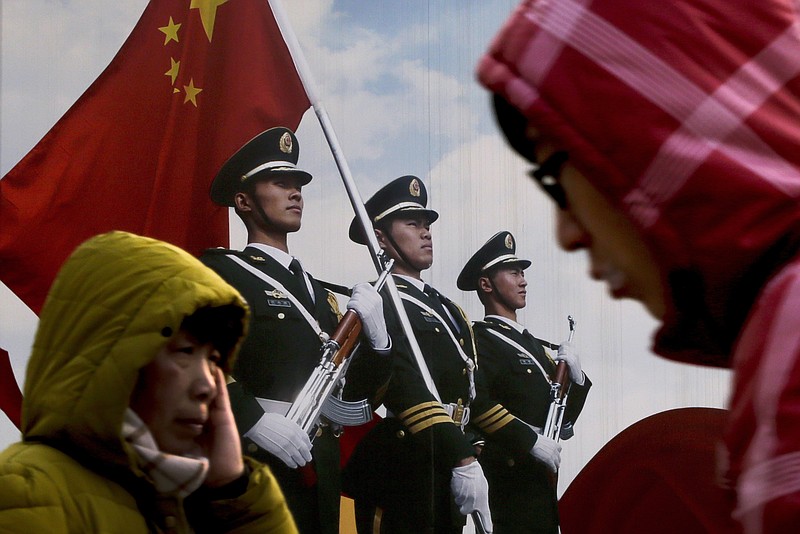 
              In this Jan. 21, 2016, file photo, people walk past a poster of Chinese People's Liberation Army (PLA) soldiers on display in Beijing. China's military is appealing to the younger generation with a slick new recruitment video featuring aircraft carriers, tanks and special forces troops, all set to a rousing rap-rock soundtrack. (AP Photo/Andy Wong, File)
            