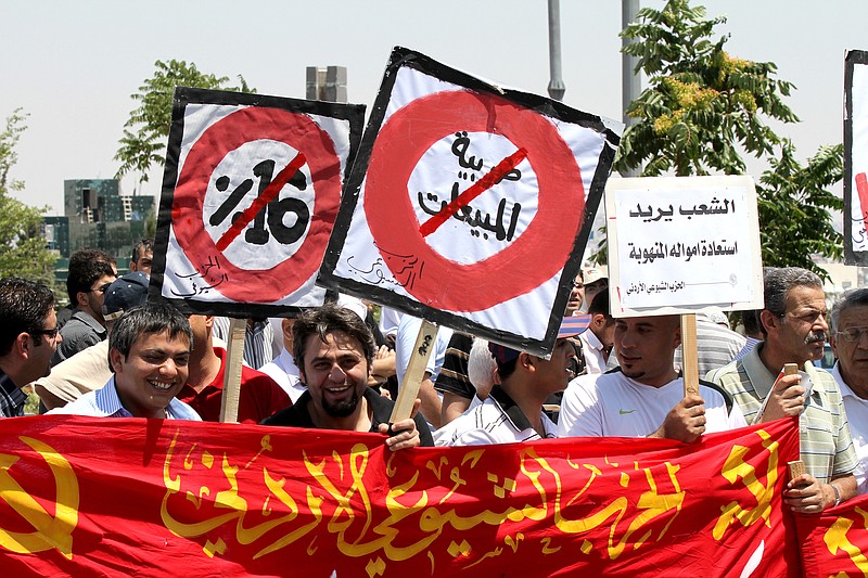 
              FILE - In this June 24, 2011 file photo, supporters of the Communist Party hold banners demanding cancellation of the sales tax during a demonstration by opposition parties demanding an end to government corruption in front of the prime minister's office in Amman, Jordan. White placard on right reads, "People want the stolen money back." A new report by an anti-corruption watchdog reveals that nearly 30 percent of people in the Middle East have had to pay a bribe to access some kind of public service and that courts had the worst bribery rate of six services asked about. (AP Photo/ Nader Daoud, File)
            