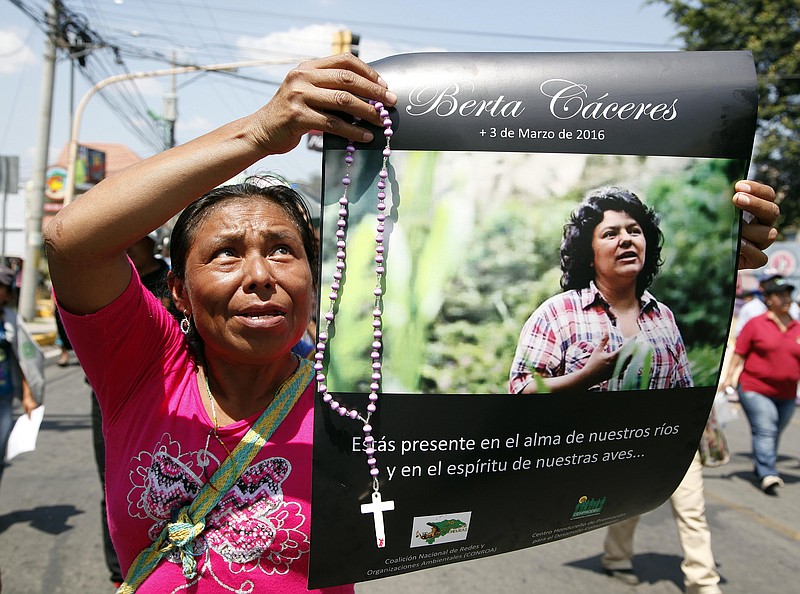
              FILE - In this March 16, 2016 file photo, a woman holds up a poster with a photo of slain environmental leader Berta Caceres during a protest in Tegucigalpa, Honduras. Caceres reported receiving threats from DESA security personnel, as well as an attempt by a company official to bribe her to call off the demonstrations, according to Billy Kyte, a senior campaigner on land and environmental defense at London-based Global Witness. DESA, or Desarrollos Energeticos SA, is the company carrying out the Agua Zarca hydroelectric project that Caceres lead protests against. (AP Photo/Fernando Antonio, File)
            