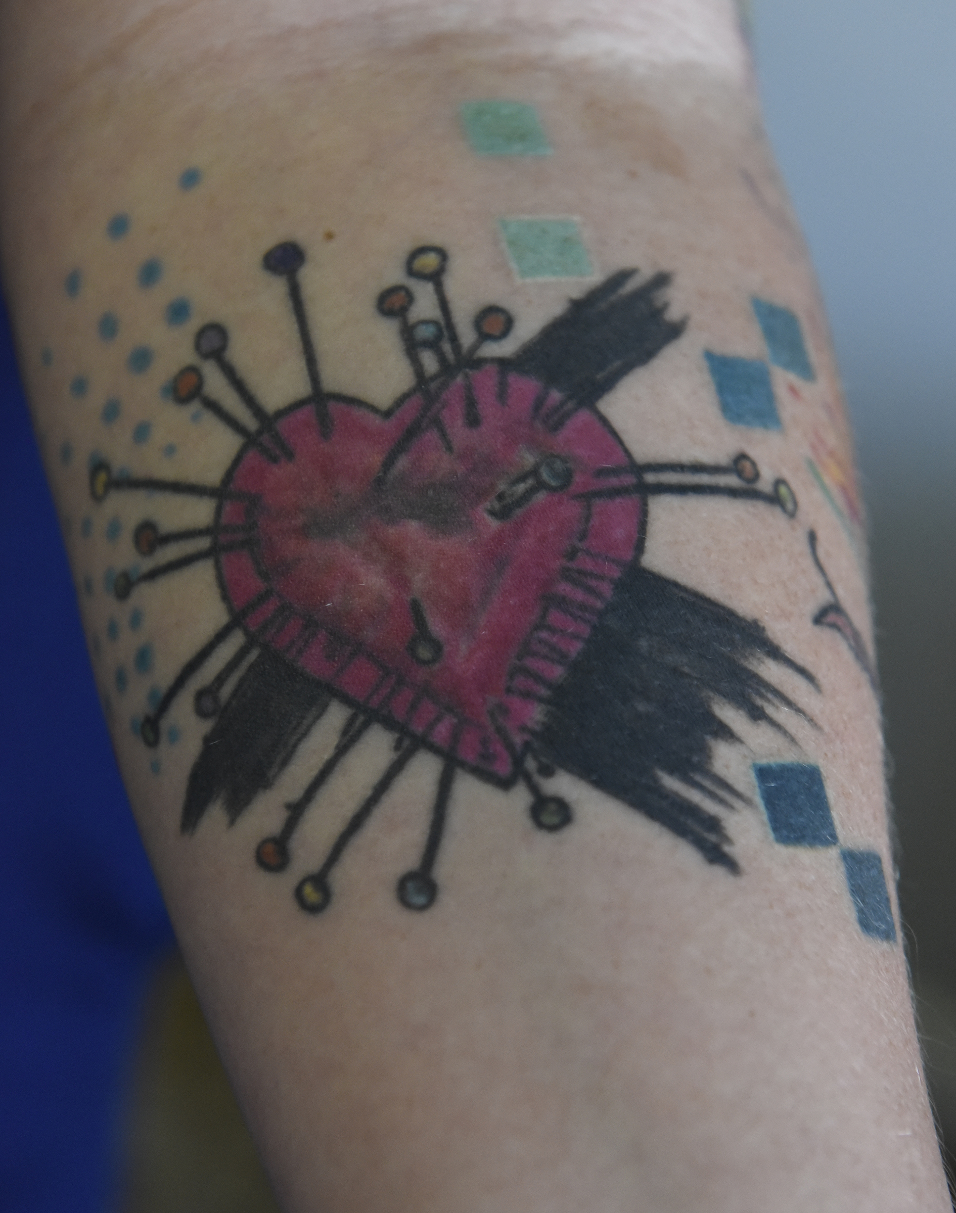 After receiving a tattoo that didn't turn out how she wanted, Angela Pierce turned to artist Jennifer Edge at Main Line Ink to fix it. Edge modified the original art to look more like a heart-shaped pincushion with cute pins instead of an angry heart with nails bursting out of it.