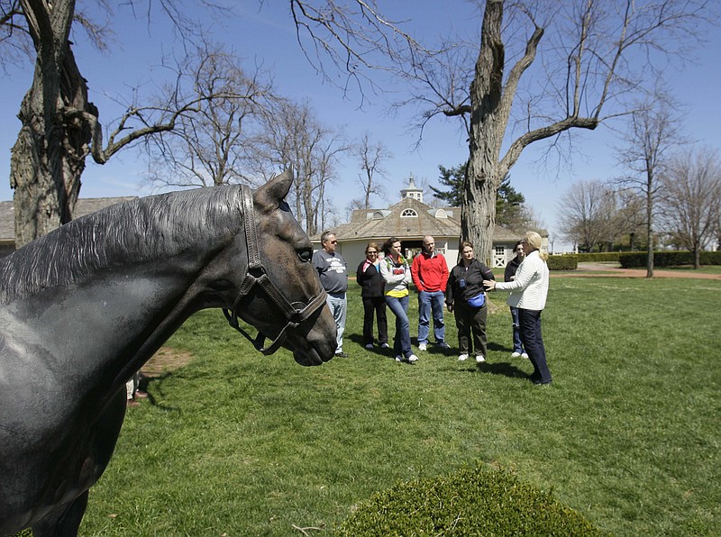 
              FILE - In this April 6, 2011 file photo, a tour group pauses in front of a statue of Seattle Slew during a tour of Three Chimneys Farm in Midway, Ky. Some of the best-known farms in Kentucky’s scenic horse country are borrowing from another of the state’s contributions to the good life - Kentucky’s bourbon whiskey distilleries - in an effort to win new recruits to an aging and shrinking fan base. Taking cues from the overwhelming success of the Kentucky Bourbon Trail, they hope to develop a thoroughbred trail with a more coordinated outreach to fans. (AP Photo/Ed Reinke, File)
            