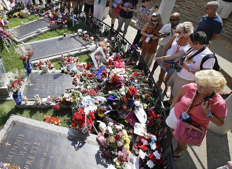 
              FILE - In this Aug. 16, 2012, file photo, Elvis Presley fans visit his grave at Graceland, Presley's Memphis, Tenn., home. The operators of Graceland said the tourist attraction centered on the life and music of Elvis Presley has received its 20 millionth paid visitor Monday, May 2, 2016. (AP Photo/Mark Humphrey, File)
            