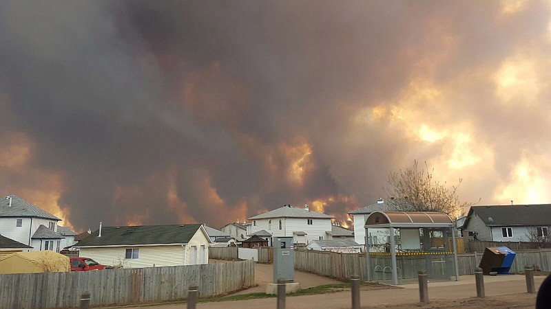 Smoke rises from a wildfire outside of Fort McMurray, Alberta, Tuesday, May 3, 2016. The entire population of the Canadian oil sands city of Fort McMurray, has been ordered to evacuate as a wildfire whipped by winds engulfed homes and sent ash raining down on residents.