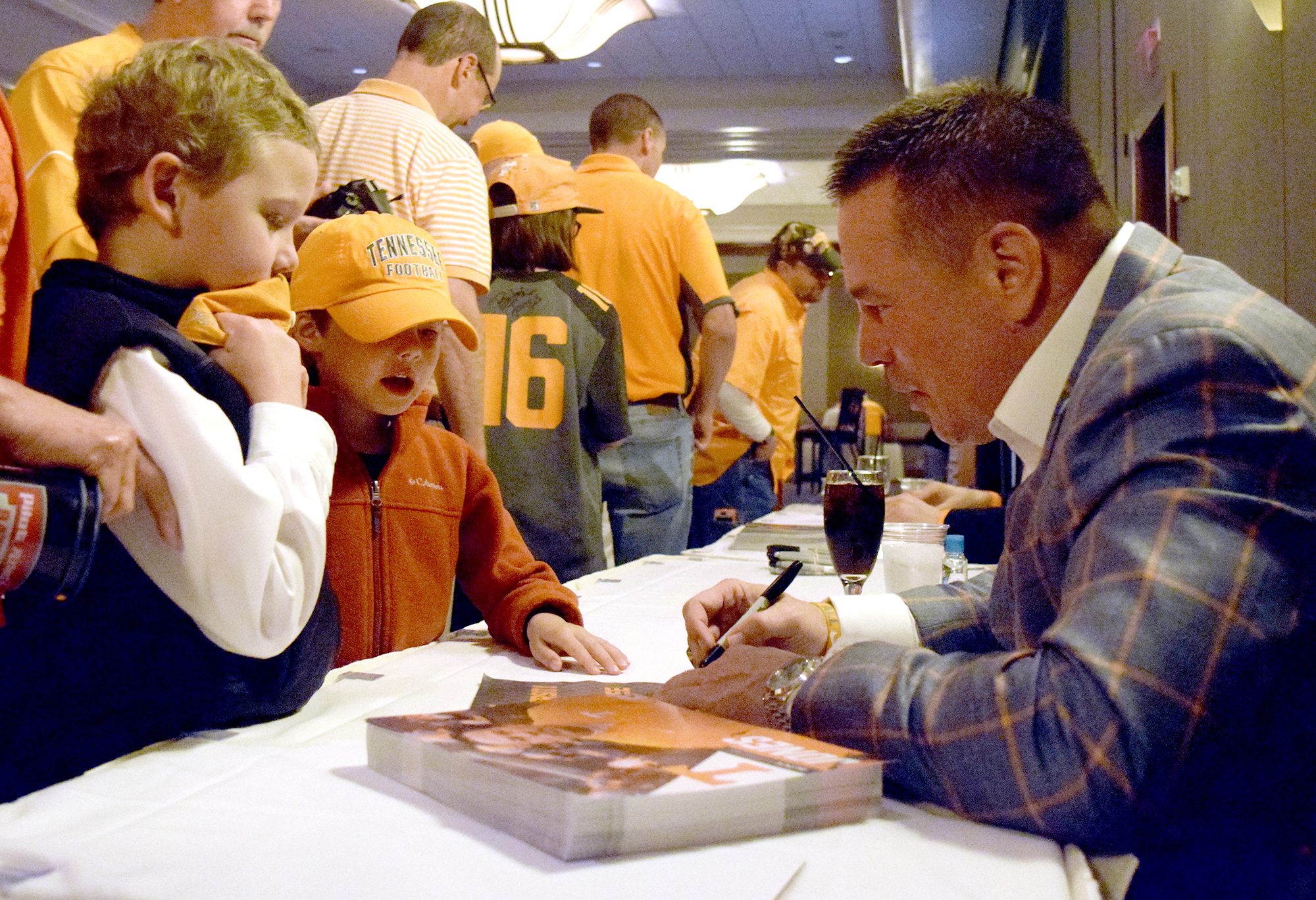 From left, Davis Guthrie, and little brother Jack, watch as UT head football coach Butch Jones signs autographs for them.  The University of Tennessee Big Orange Caravan rolled into town at the Chattanoogan on Thursday May 5, 2016.