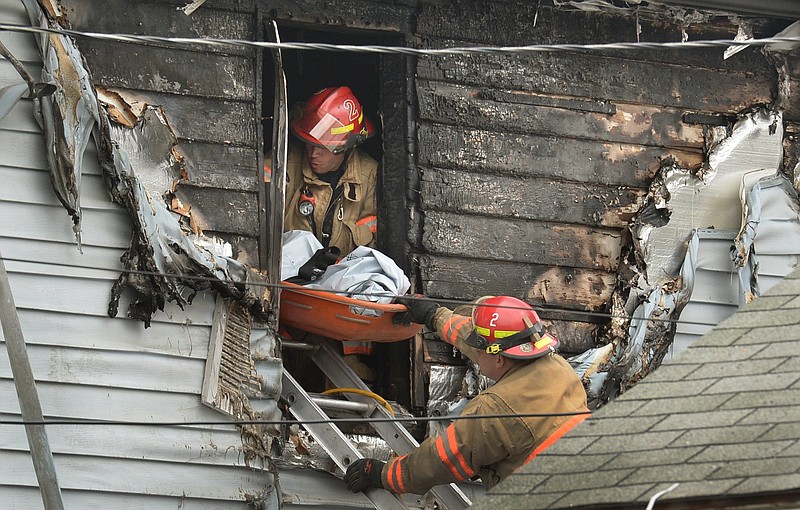 
              Syracuse firefighters remove a body through an upstairs window at the scene of a fatal fire Friday May 6, 2016 in Syracuse, N.Y. The blaze was reported early Friday morning.  When firefighters arrived just minutes after receiving a 911 call, the front of the house was engulfed in flames, officials said.   (David Lassman/The Syracuse Newspapers via AP) NO SALES; MANDATORY CREDIT
            