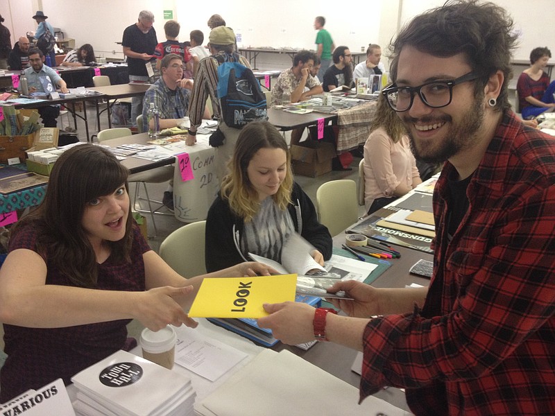 Chattanooga Zine Fest co-founder Aggie Toppins, left, and 2015 volunteer coordinator designer Julie Heavner swap a zine from Aggie's Octagon Press with zine makers from Toronto.