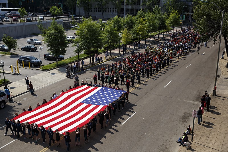 Bands from multiple high schools march with an American flag ahead during the Armed Forces Day Parade on Friday, May 6, 2016, in Chattanooga, Tenn. This was the first Armed Forces Day Parade since last July's shootings at military facilities in which five service members were killed.