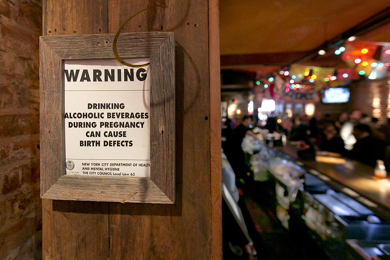 
              The drinking and pregnancy warning notice is posted behind the bar at the Mad Dog & Beans Mexican Cantina, in New York's Financial District, Friday, May 6, 2016. Pregnant women can't be barred from New York City bars or refused alcoholic drinks just because they're expecting, under new official guidance on a city rights law. Human Rights Commission officials say they're not saying that expectant mothers should drink, but that such health decisions are up to the woman, not a bartender. (AP Photo/Richard Drew)
            