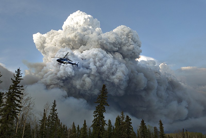 
              A helicopter flies past a wildfire in Fort McMurray, Alberta on Wednesday, May 4, 2016. Alberta declared a state of emergency Wednesday as crews frantically held back wind-whipped wildfires that have already torched homes and other buildings in Canada's main oil sands city of Fort McMurray, forcing thousands of residents to flee. (Jason Franson /The Canadian Press via AP) MANDATORY CREDIT
            