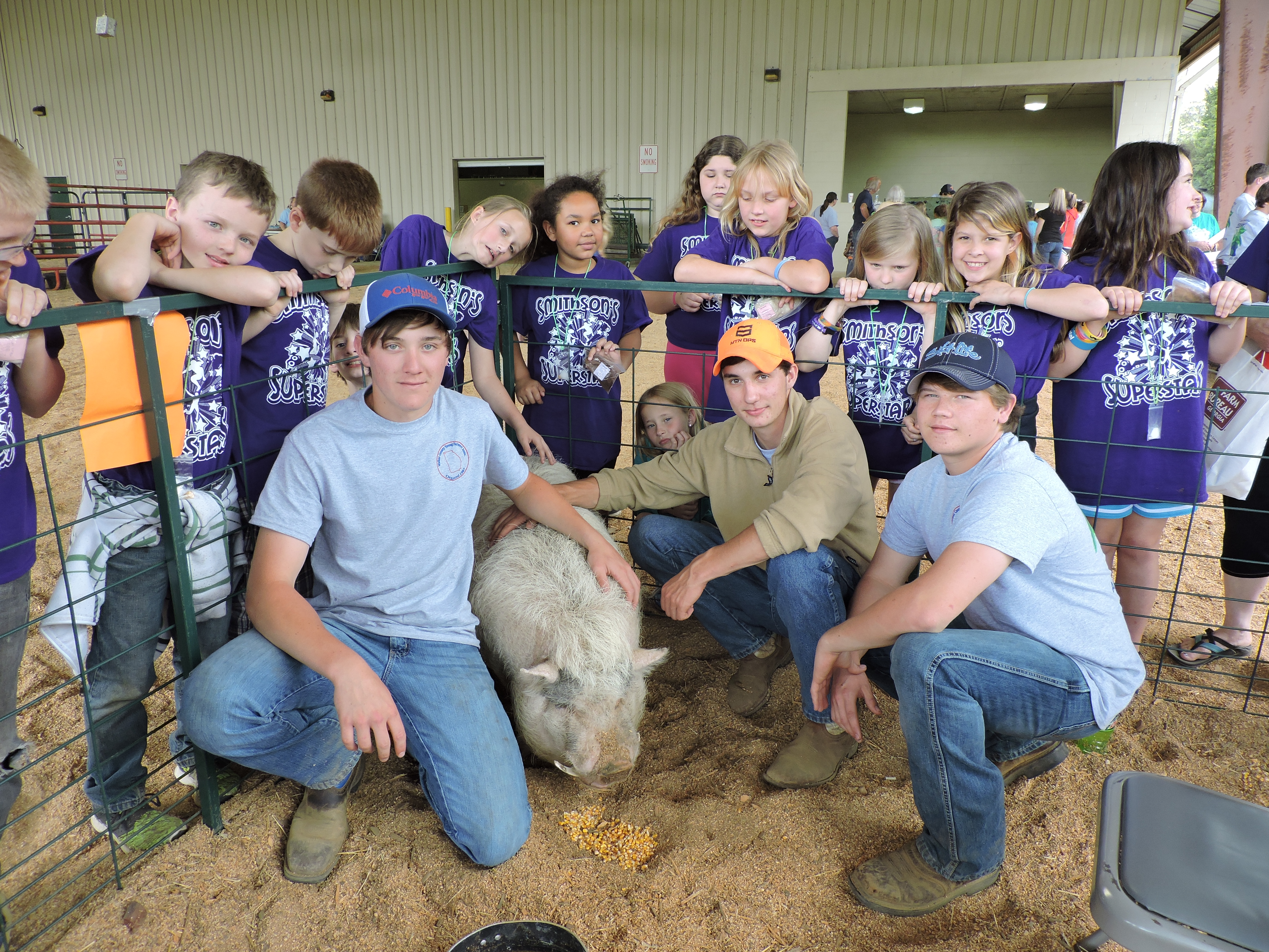 Kneeling beside Korky the pig are LaFayette High School students Devin Bradley, Nick Glover and Tucker Reeves, from left. Students from Cherokee Ridge Elementary School stand behind them. Devin told the students that Korky weighs 250 pounds and that pork meat production involves bacon and ham. Piglets nurse on their mother for six weeks, he said.