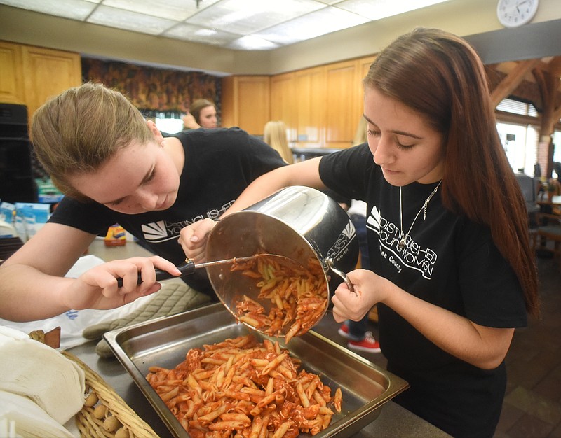 Myah Arnold holds a pot of pasta steady while Sarah Simmons scrapes the food into a pan. The teens are contestants in the Distinguished Young Woman of Rhea County program who volunteered to prepare dinner for families living in the Chattanooga Ronald McDonald House.