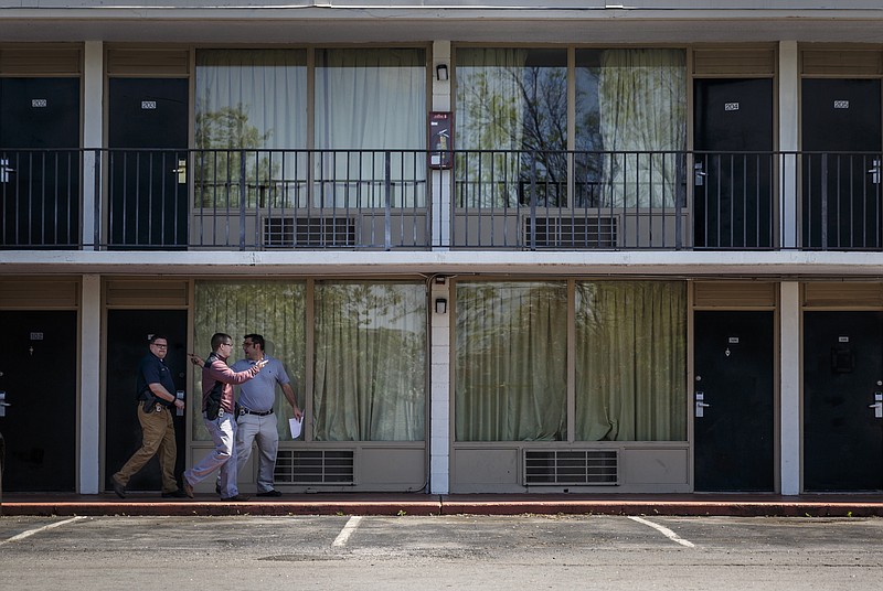 Chattanooga police investigators walk Friday, March 25, 2016, past rooms at the Chatt Inn, where the body of Jeanette Scholten, 34, was found the day before after hotel managers notified police that she hadn't been seen for several days.