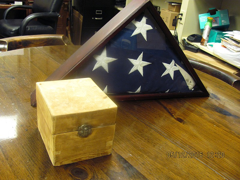 
              This Thursday, May 5, 2016 photo, provided by the Florala Police Department, shows a box and a flag sitting on a table after a south Alabama police chief says a power line crew found the abandoned small pine box with a rusted lock and an American flag. The police chief says he has a few leads but still no answers to explain how a box of human ashes was found beside a highway near the Florida line. (Florala Police Department, via AP)
            