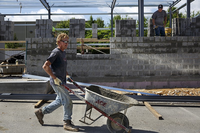 James Thomas wheels a wheelbarrow of cement while Jeff Burdett constructs a wall as construction continues on a new warehouse and fabrication facility at Southern Fluid Power on Friday, May 13, 2016, in Chattanooga, Tenn.