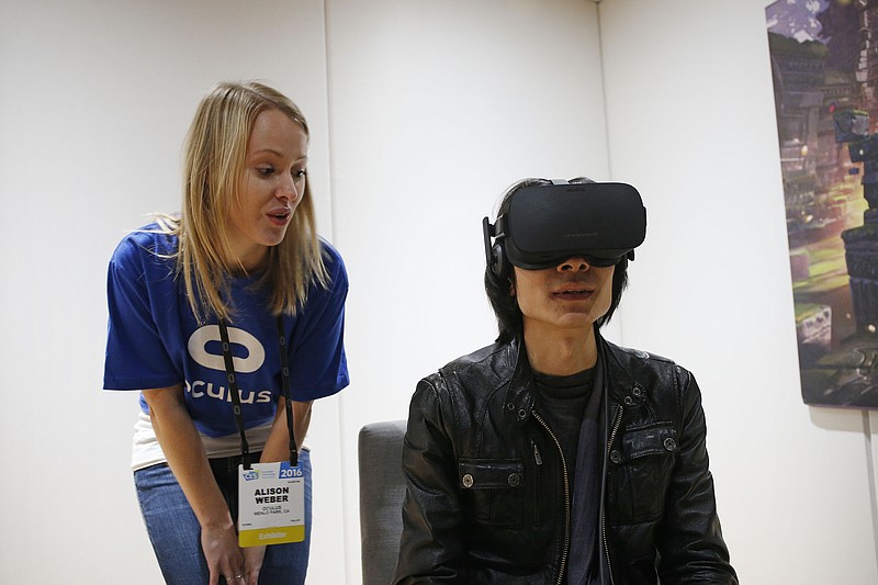 
              FILE - In this Jan. 6, 2016 file photo, Alison Weber, left, instructs Peijun Guo on using the Oculus Rift VR headset at the Oculus booth at CES International in Las Vegas. Oculus has responded to Sen. Al Franken's questions about consumer privacy when using the Oculus Rift virtual reality system. They say collecting the physical movements of users is a necessary tool to deliver "a safe, comfortable and seamless VR experience." (AP Photo/John Locher, File)
            