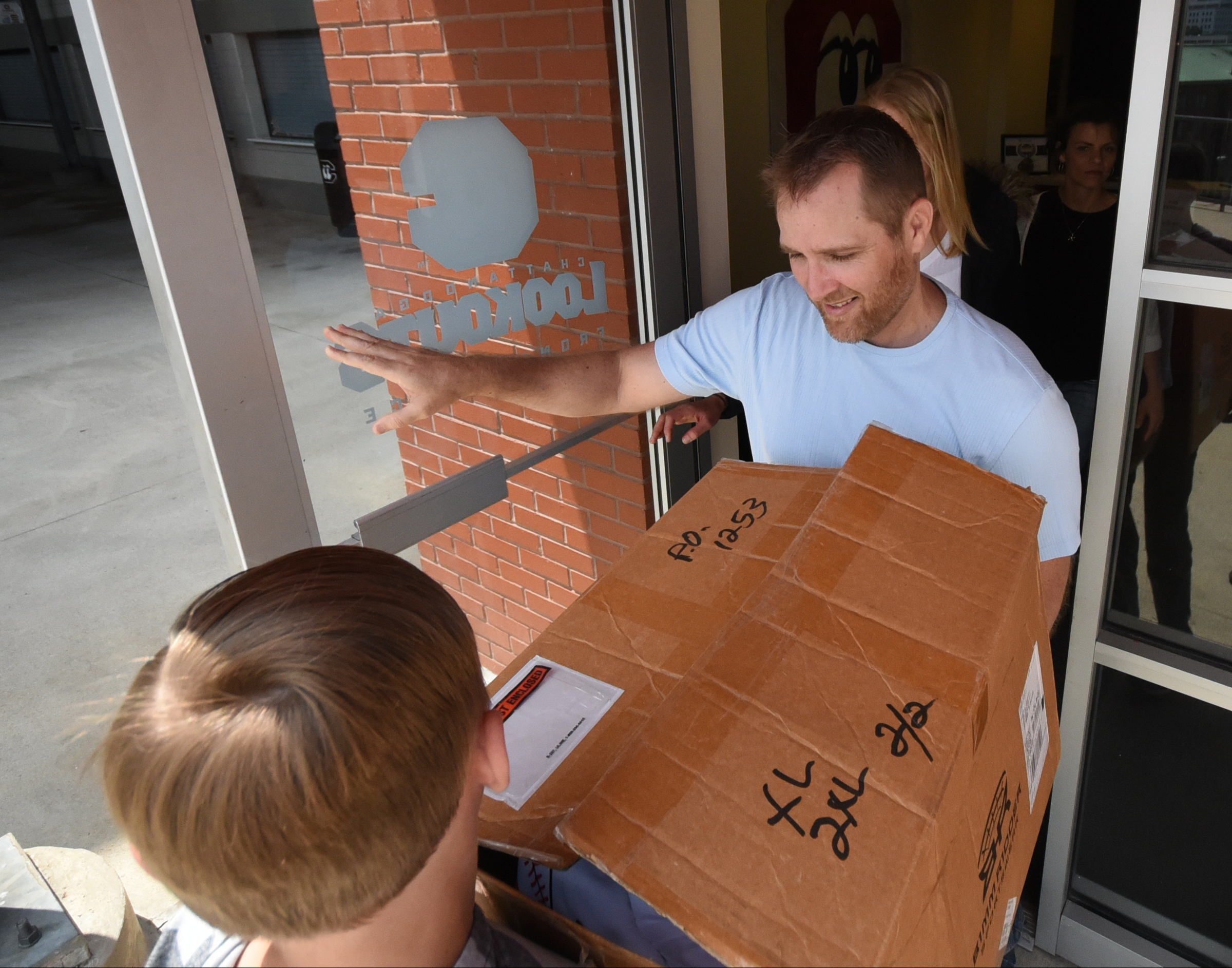 Jimmy Larche, center, and his son, Zach, left, transport donations of sportswear from the Lookouts' front office. Breakaway Outreach, which Larche helped create, will distribute the items to Iraqi, Syrian and Sudanese refugees in Germany.