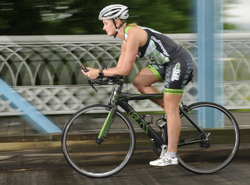 Noel Reagan does a warm up ride across the Walnut Street Bridge on Friday. Reagan is a flight attendant for Delta Airlines and trains for events like the Ironman 70.3 in far away locations while working all over the world.