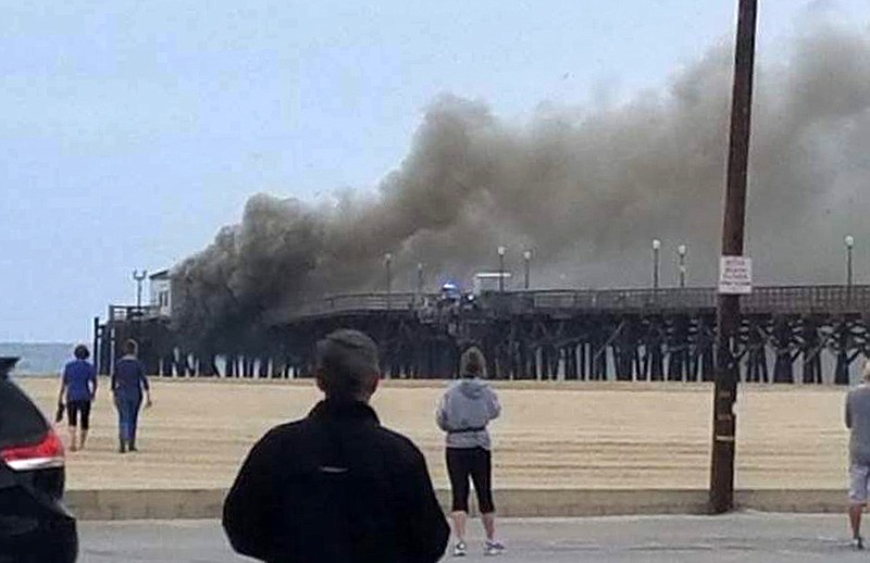 
              This photo provided by Amy Stanton shows a large plum of smoke from a fire burning on the Seal Beach pier in Seal Beach, Calif., on Friday, May 20, 2016. A fire is burning on a former restaurant on Southern California's Seal Beach Pier. The blaze erupted early Friday at the end of the long wooden pier southeast of Los Angeles. Harbor patrol boats are attacking the flames with streams from water cannons while firefighters direct streams from hoses on the pier. (Amy Stanton via AP)
            
