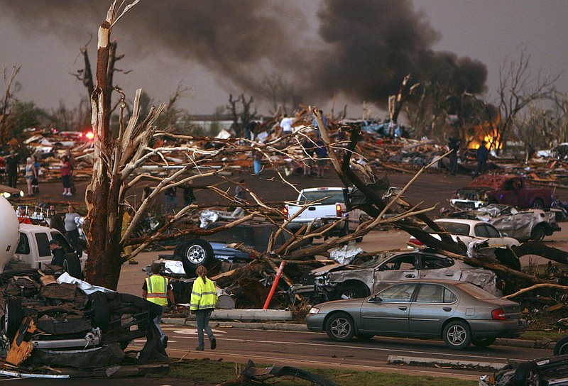 
              FILE - In this May 22, 2011 file photo, emergency personnel walk through a severely damaged neighborhood after a tornado hit Joplin, Mo. A sky-darkening storm was working its way into southwest Missouri around dinnertime on a Sunday evening of May 22, 2011, zeroing in on the city of Joplin. Forecasters knew the storm's potential was fierce and gave early warnings. Then, as storm sirens blared, one of the nation's deadliest tornados hit _ leveling a miles-wide swath of Joplin and leaving 161 people dead. (AP Photo/Mark Schiefelbein, File)
            