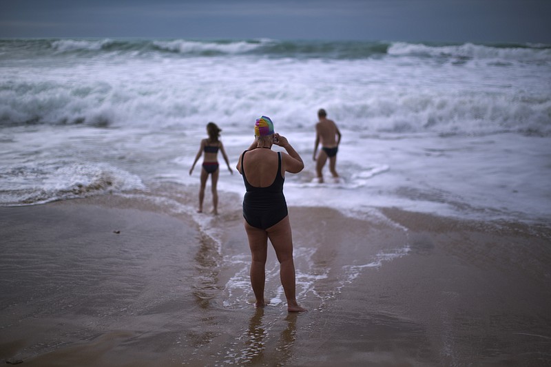 
              FILE- In this Jan. 1, 2014 file photo, German tourists walk on the seashore as one of them takes a photograph, after swimming in the Atlantic ocean in a beach in Cadiz, southwest Spain. Nudists have lost a seven-year legal battle for access to a popular tourist resort beach on Spain's southwestern tip. (AP Photo/Emilio Morenatti, File)
            