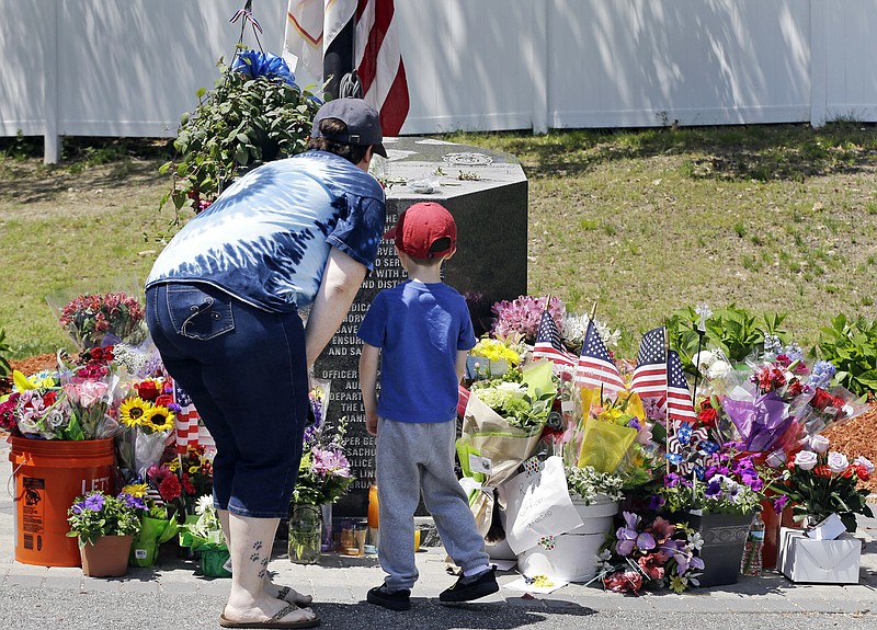 
              Danielle Dowd and her son Lucas pause before a memorial set up for slain Auburn police Officer Ronald Tarentino outside the police station, Monday, May 23, 2016, in Auburn, Mass. The man suspected of killing Tarentino during a weekend traffic stop had a lengthy criminal record and had been released from a maximum-security prison in 2013, officials said Monday. (AP Photo/Elise Amendola)
            