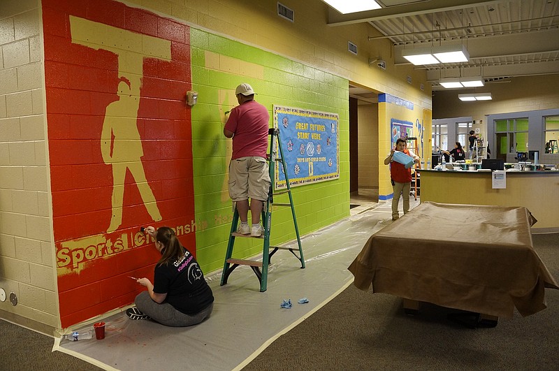 A group of T-Mobile employees repaints the Boys & Girls Club's walls. Tim Krug, T-Mobile call center director, said the walls were "flat" and "gray" when he walked in that morning, but by the end of the day, they shone with vibrant colors and messages.