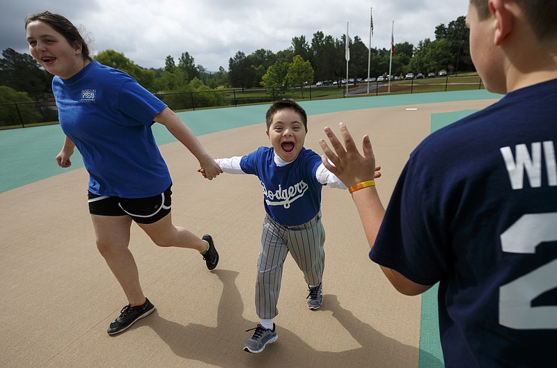 Dodgers player Joshua Castaneda, center, high-fives Yankees player William Hiestand as he rounds the bases with Jadyn Bennett, left, during a Miracle League ballgame at the Miracle Field on Saturday, May 21, 2016, in Rocky Face, Ga. Fundraising efforts are underway to bring a Miracle Field to Warner Park in Chattanooga.