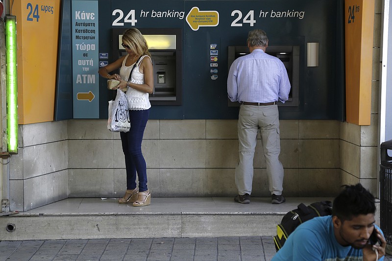 
              A man, right, speaks on his mobile phone as people use ATM machines outside a bank of Cyprus' branch in central capital Nicosia, eastern Mediterranean island of Cyprus, on Friday, May, 20, 2016. Knuckling down and doing away with wasteful spending while avoiding burdening working folks with more taxes helped Cyprus wrap up a three-year, multibillion euro rescue plan and emerge with solid growth and a dropping, but still high unemployment rate. (AP Photo/Petros Karadjias)
            