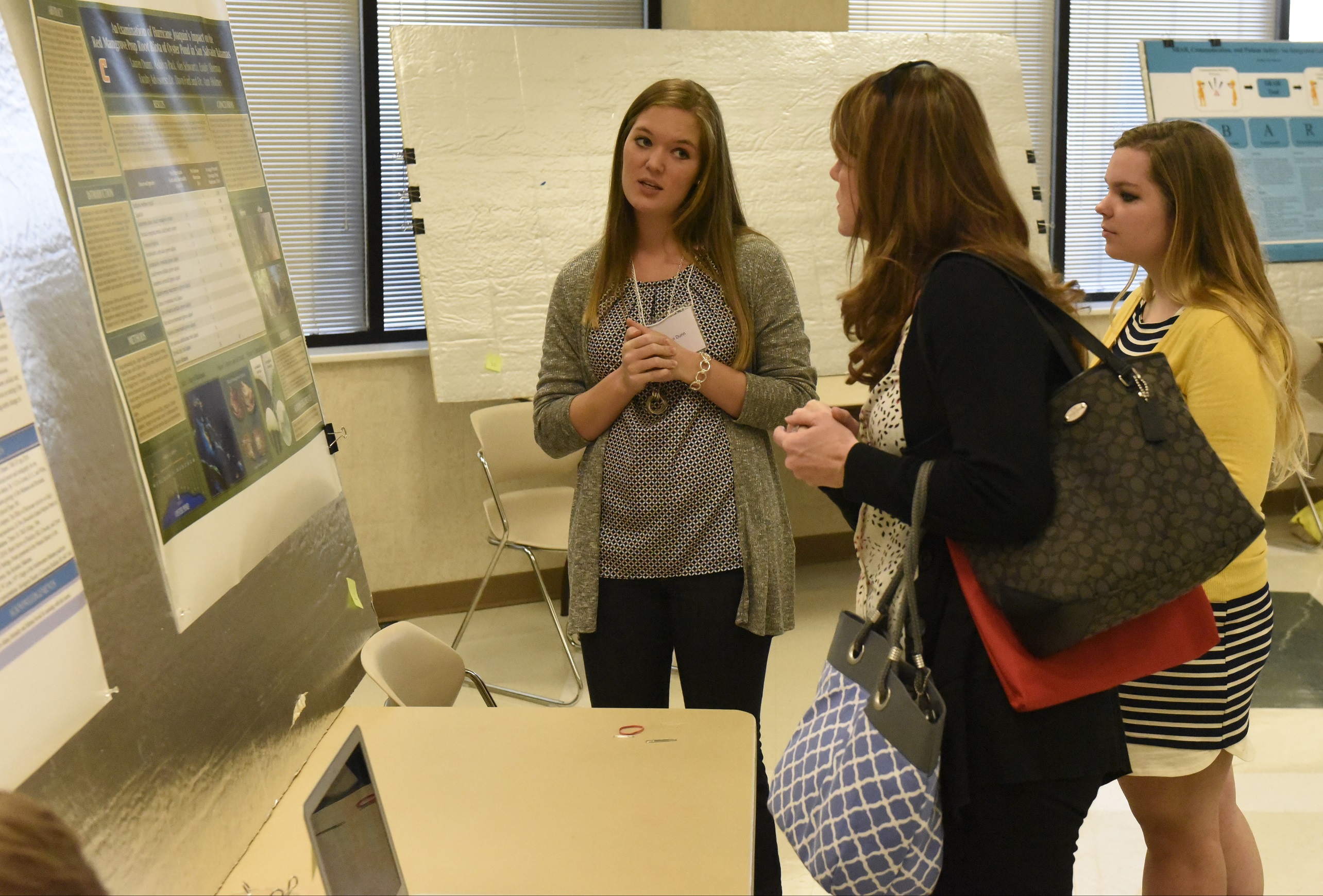 Lauren Dunn, left, and Sara Leach, right, UTC students who travelled to the Bahamas to do biological and geological research, talk to Jessica Etheredge (CQ), a professor of interior architecture, as they present a display about their findings on Wednesday, Apr. 13, 2016, in Chattanooga, Tenn.