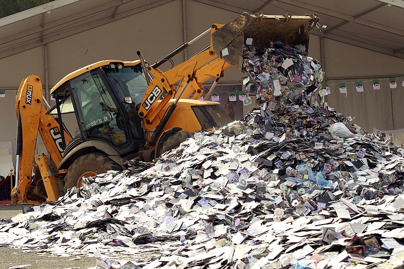 
              In this photo taken Monday, May 23, 2016,  a backoe-loader crushes illegally made CDs and DVDs in the Algerian capital, Algiers. Power shovels and bulldozers have destroyed a huge mound of 2 million illegally copied CDs and DVDs outside Algeria’s Culture Ministry, as part of a government pledge to crack down on long-rampant piracy.  (AP Photo)
            