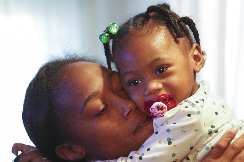 Zoey Duncan hugs her mother Bianca Horton while at their apartment on Thursday, January 7, 2016. One year ago a gunman opened fire in a College Hill Courts apartment, killing a 20-year-old woman and wounding three others, including 1-year-old Zoey Duncan, who barely survived. Zoey was paralyzed from the waist down. A year later, she now gets around in a tiny toddler-sized pink wheelchair. Bianca Horton was found dead on the side of Elder St Wednesday morning.