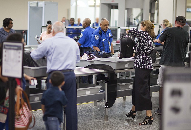 A TSA official helps passengers load their carry-on belongings onto an automated conveyer belt at a newly designed passenger screening lane unveiled at Hartsfield-Jackson Atlanta International Airport Wednesday, May 25, 2016, in Atlanta. The new screening lanes allow multiple passengers to load their belongings onto an automated conveyer belt at the same time. The lanes, the first of its kind in the nation, are aimed at speeding up the security process and are modeled on similar systems at London's Heathrow and Amsterdam's Schiphol airports. (AP Photo/David Goldman)