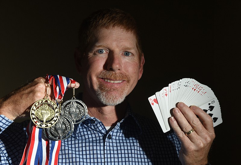 Dr. Brad Sundstrom, a dental surgeon in Chattanooga, holds his medals from memory competions and a deck of cards which he can memorize — in random order — in a matter of minutes, one of the tasks he must complete in the contests.