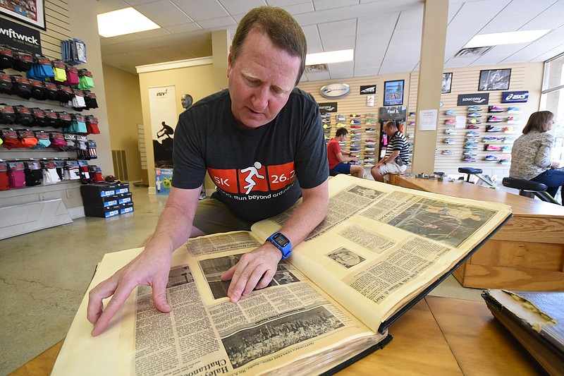 Joey Howe looks through a scrapbook of clippings from past Chattanooga Chase events on Friday at the Fast Break Athletics store on Cherokee Boulevard. The scrapbook is owned by longtime runner Sue Anne Brown.