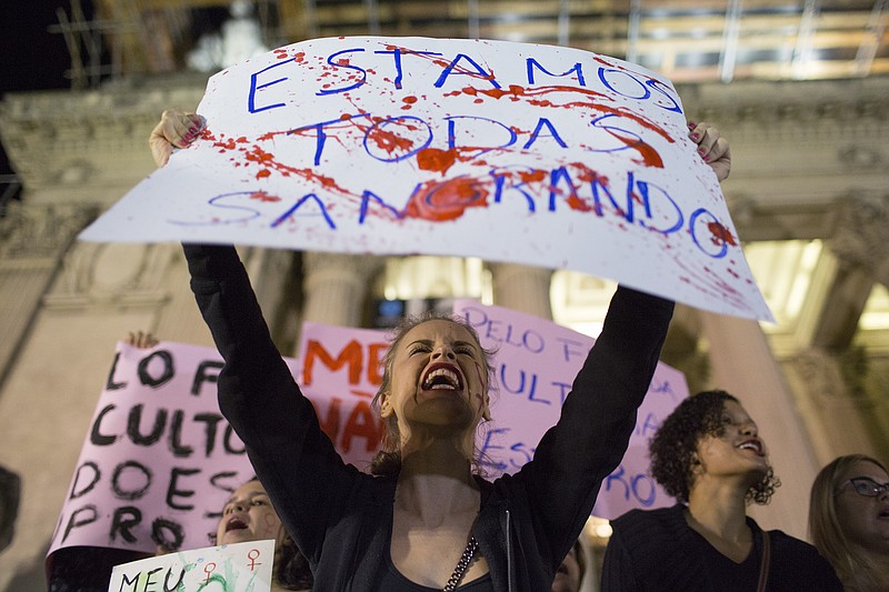 
              A woman shouts holding a banner that reads in Portuguese "We're all bleeding" as she protests the gang rape of a 16-year-old girl in Rio de Janeiro, Brazil, Friday, May 27, 2016. The assault last Saturday came to light after several men joked about the attack online, posting graphic photos and videos of the unconscious, naked teen on Twitter. (AP Photo/Leo Correa)
            