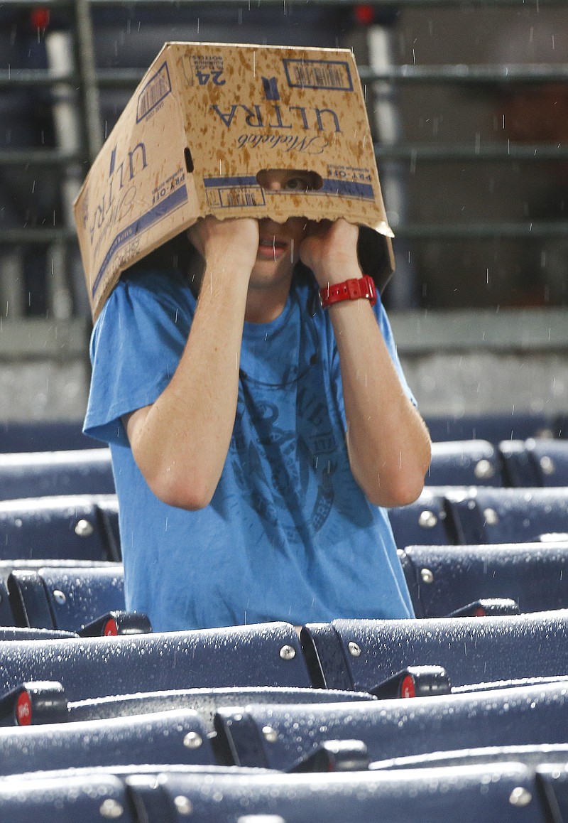 A young fan takes cover from the rain under a cardboard box in the seventh inning of a baseball game between the Milwaukee Brewers and the Atlanta Braves on Thursday, May 26, 2016, in Atlanta. (AP Photo/John Bazemore)