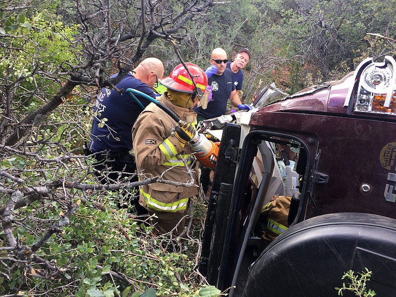 
              This photo provided by Kim Moore shows firefighters working to extricate a 50-year-old man from his crashed car on Mingus Mountain in Yavapai County, Arizona on Friday, May 27, 2016. Authorities say a man trapped in his crashed vehicle on a central Arizona mountain for three days was rescued thanks to a couple taking sightseeing photos.  (Kim Moore via AP)
            