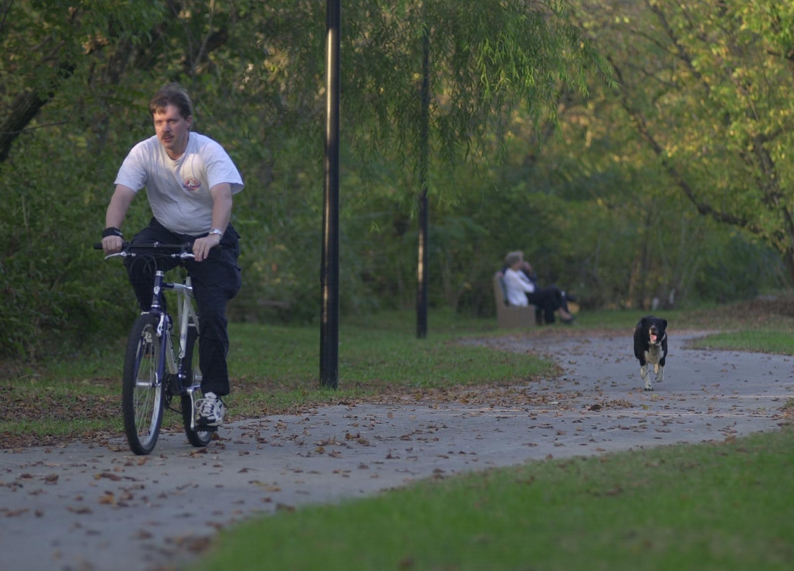 Staff Photo by John Rawlston Followed by Louie, a neighbor's dog, Barry Kirkpatrick rides his bike along the Mouse Creek Greenway in Cleveland. Work is scheduled to begin on the next phase of the pathway, funded with a $750,000 federal grant.