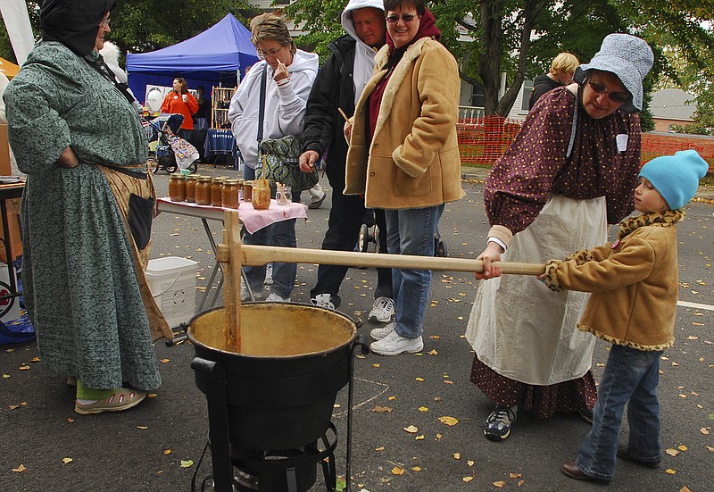 Judy Baker, left, demonstrates to Alanea Daniels, 5, the proper way to churn apple butter at the Apple Festival in Cleveland, Tenn. Ms. Baker works with Those Things Traditional, a business based in Tennessee dedicated to preserving traditional technology.