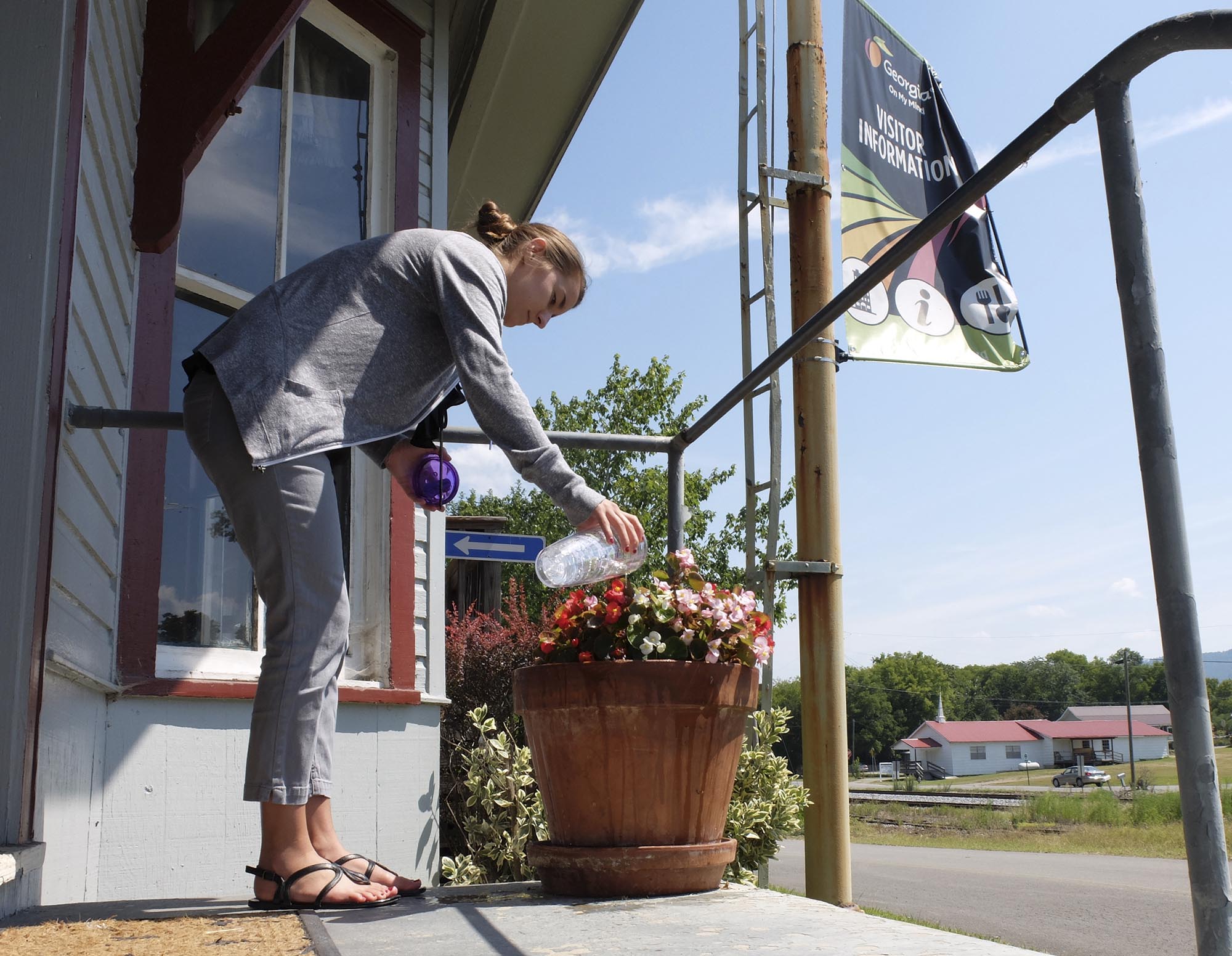 Dade County Chamber and Welcome Center Information Specialist Madeline Barton waters the flowers on the porch of the old Trenton Depot on Tuesday Work continues on the new offices for the Chamber of Commerce and Visitors Center to be located in the old Dade County Courthouse. The courthouse is being updated for ADA compliance.