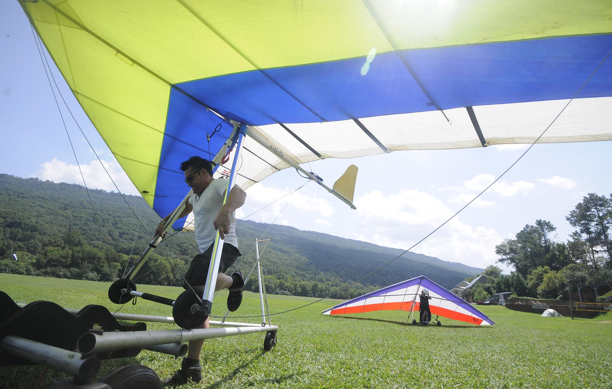 Dana Daniels, a mobile disc jockey from Atlanta, moves his glider into position for transport after a 20- minute flight from the top of Lookout Mountain Flight Park. "I got about 1,000-feet above the mountain just after take-off," Daniels said. Jen Richards, back, and employee in the pro-shop atop Lookout Mountain, walks her glider to the break-down area after landing.