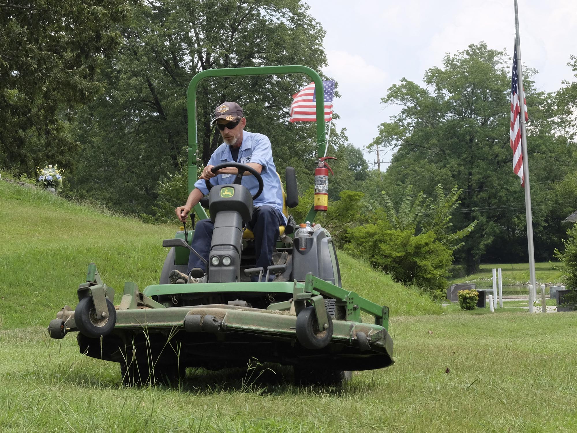 Steve Wells, 15-year employee at Chattanooga Memorial Park, flies his American flag atop his work equipment Tuesday along Memorial Drive in Red Bank. "I just put this flag on yesterday," Wells said, in response to last weeks tragedy.