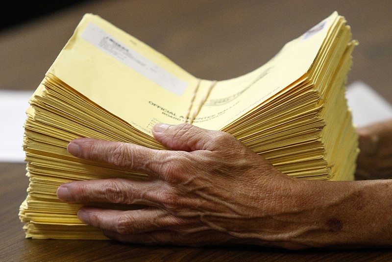 An elections official holds counted absentee ballots on primary election night at the Walker County Courthouse last week, when voters in a nonbinding referendum said they'd like a new form of government.